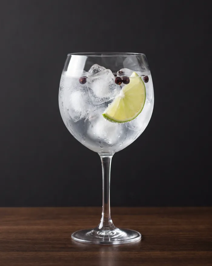 Gin tónico servido em copo balão com lima